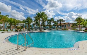 Une piscine bordée de palmiers, avec des chaises longues et un espace abrité.