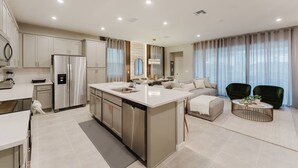 Een moderne keuken met roestvrijstalen apparatuur, een centraal eiland en een zithoek met een bank en stoelen.