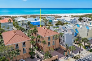 Un quartier résidentiel situé sur la côte, avec des bâtiments, des palmiers et une plage en arrière-plan.