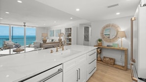A modern kitchen with a large island, white cabinetry, and a view of the ocean. - Stunning Condo at Crystal Sands on Siesta Key! (Siesta Key)