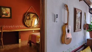 Et værelse med en seng, en guitar, et spejl og en vægmonteret termostat.