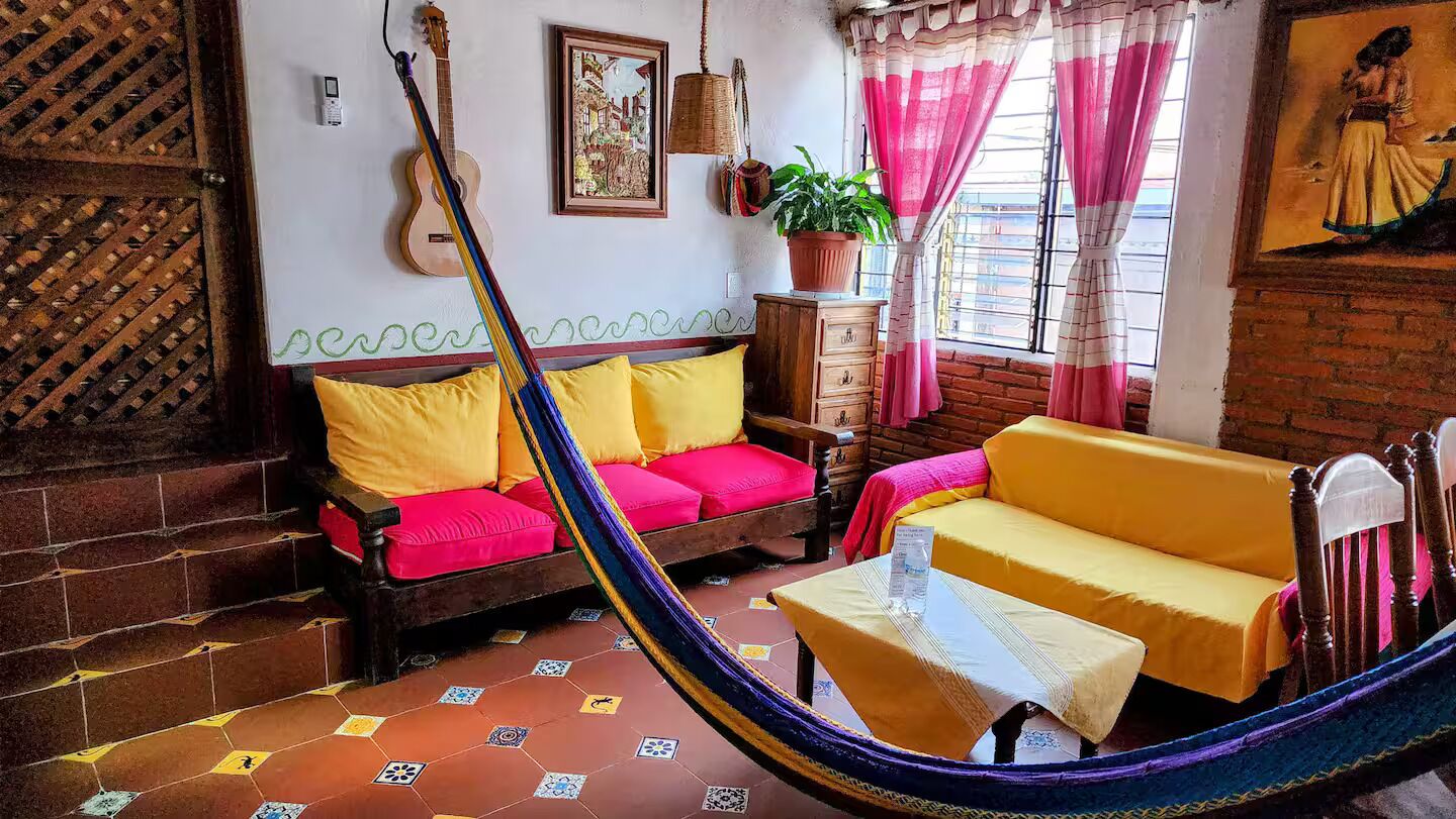 A cozy room with a hammock, a guitar, and a potted plant.
