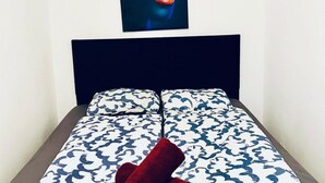A bed with a patterned bedspread, a dark headboard, and a poster on the wall. - Comfortable Room by Währinger Park, Shared Apt (Vienna)