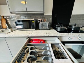 A kitchen with a microwave, toaster, stove, and a drawer organizer with utensils. - Central Apt Sleeps 8 | Bars, Restaurants & Parking (Liverpool)