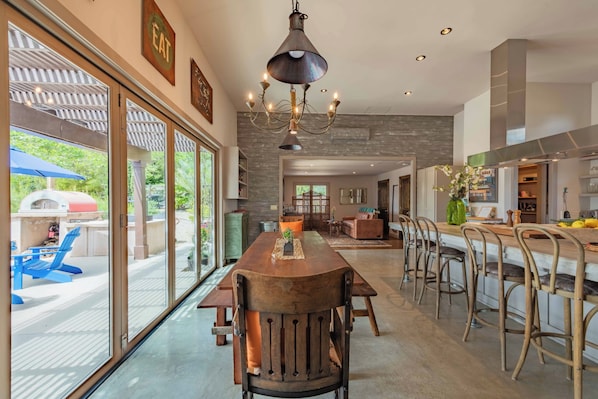 A spacious kitchen with a central island, bar stools, and a chandelier.