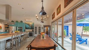 A spacious kitchen with a long wooden table, bar stools, and a chandelier. - 2 Culinary Suites in the heart of Wine Country! (Paso Robles)