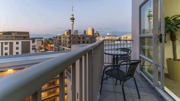Un balcón con vista a un paisaje urbano, incluyendo una torre y edificios.