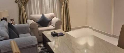 A modern hotel room with a marble dining table, a sofa, and a chair.