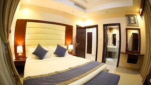 A hotel room with a large bed, bedside lamps, a mirror, and a door leading to a bathroom. - SAS OLAYA Hotel apartments (Al Khobar)