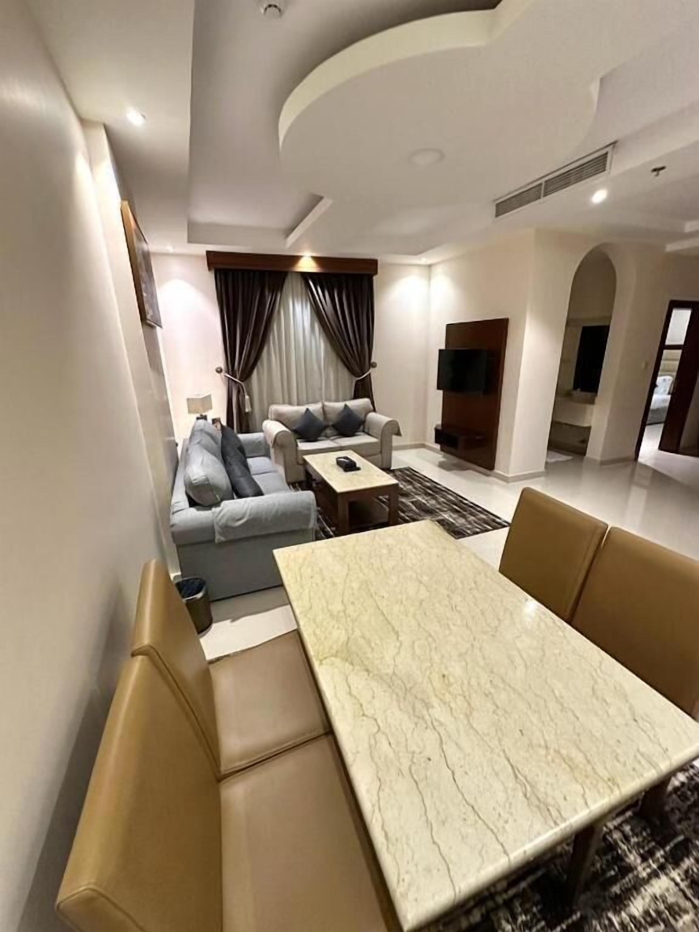 A modern living room with a marble coffee table, a sofa, and a TV.