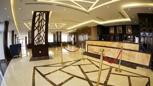 A hotel lobby with a marble floor, a reception desk, and a decorative pillar. - SAS OLAYA Hotel apartments (Al Khobar)