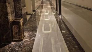 A long, well-lit hallway with marble flooring, doors on both sides, and a modern ceiling design. - SAS OLAYA Hotel apartments (Al Khobar)