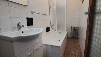 Ein kleines Badezimmer mit einem weißen Waschbecken, einem Spiegel und einer Dusche.