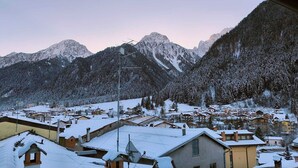 A snow-covered mountain village with traditional chalet-style buildings, a ski lift, and a clear view of the surrounding peaks. - GREEN DOLOMYTE Apartment (Schilpario)