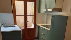 A compact kitchen with a sink, cabinets, and a wooden table. - GREEN DOLOMYTE Apartment (Schilpario)