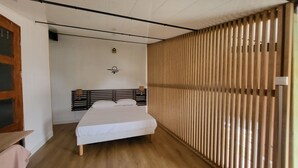 Quarto com estrutura de cama de madeira, colchão branco e piso de madeira.