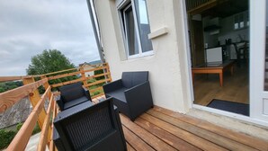 Varanda com móveis de vime e deck de madeira.