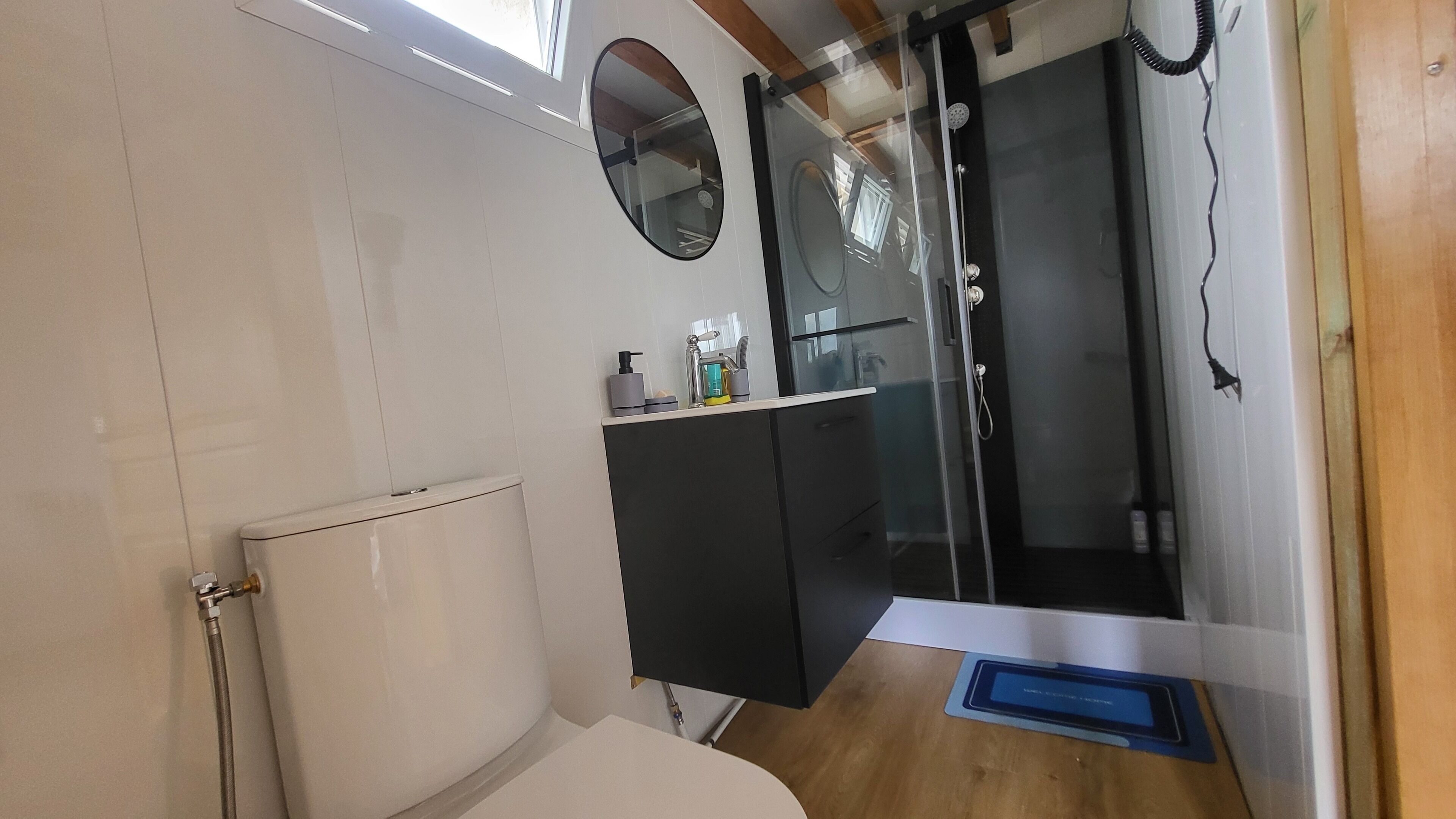 A compact bathroom with a toilet, a sink with a mirror, and a shower area.