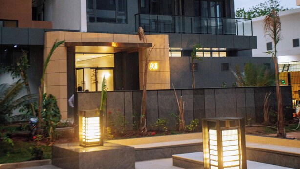 Un edificio moderno con varios balcones y un área exterior iluminada, con asientos e iluminación decorativa.