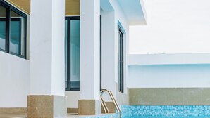 Una piscina interior con agua cristalina azul, paredes blancas y una zona de terraza de madera.