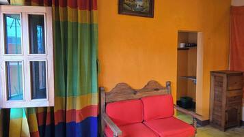 A room with a wooden bed, colorful curtains, a painting on the wall, and a cabinet.