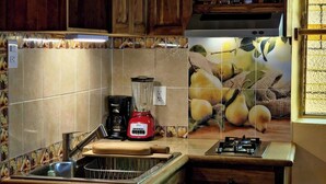 A kitchen with wooden cabinets, a gas stove, a coffee maker, and a blender. - Sofia's Shawl (Oaxaca de Juárez)