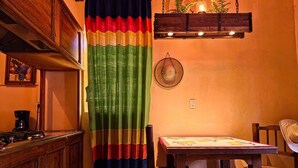 A cozy kitchen with wooden cabinets, a coffee machine, a table with chairs, and a colorful curtain. - Sofia's Shawl (Oaxaca de Juárez)