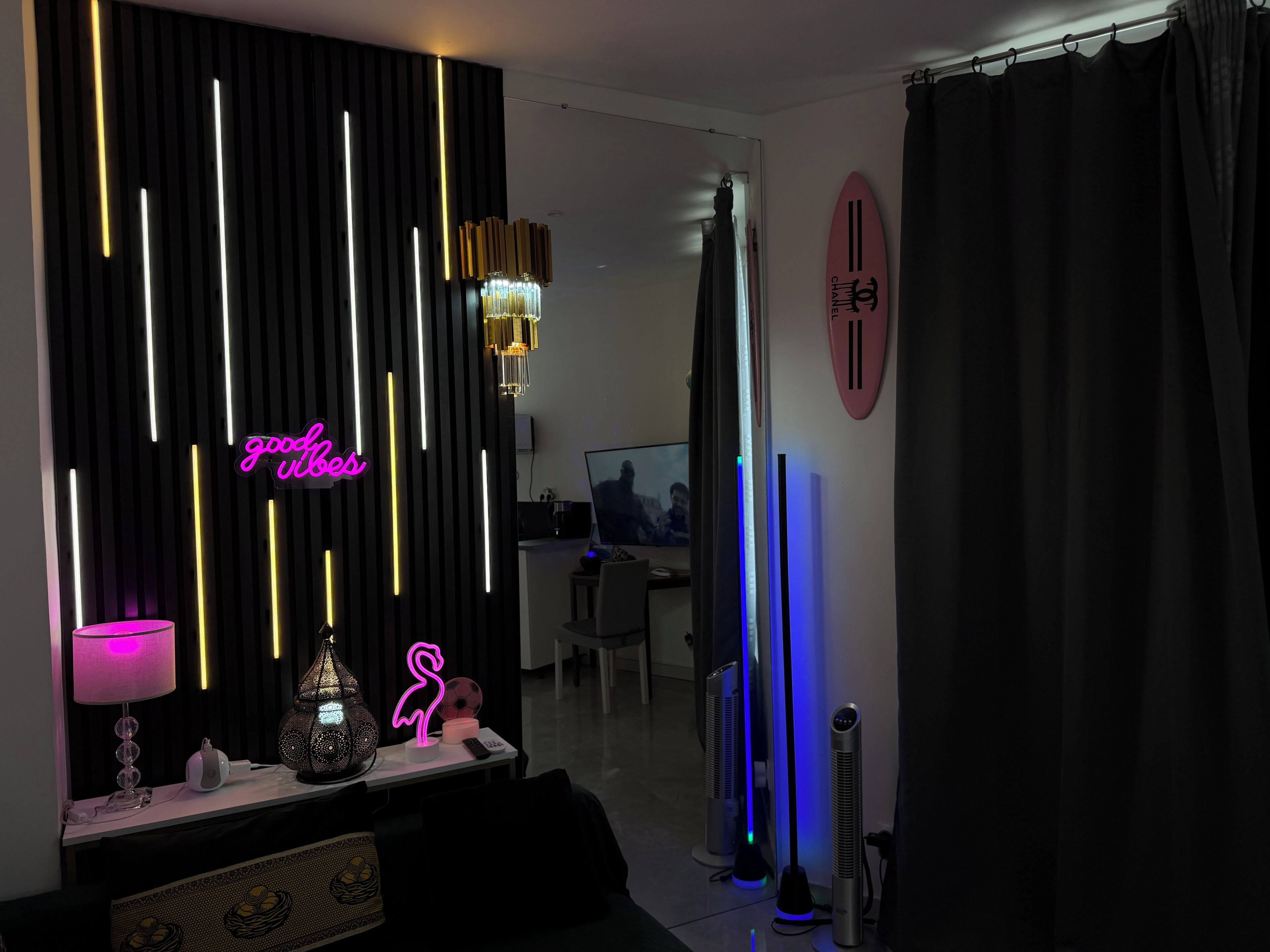 A modern living room with a neon sign, a chandelier, and a flat-screen TV.