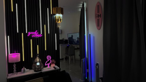 Una sala de estar moderna con un letrero de neón, una araña y un televisor de pantalla plana.