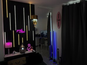 Una sala de estar moderna con un letrero de neón, una araña y un televisor de pantalla plana.