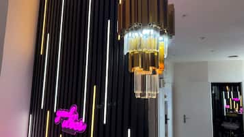 Un intérieur moderne avec un éclairage vertical en forme de bande lumineuse, un lustre suspendu et un panneau lumineux au néon.