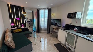 Una sala de estar moderna con un sofá, una televisión y una zona de cocina con un microondas.