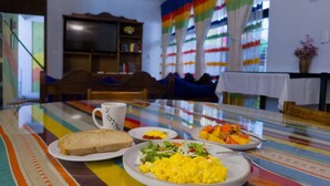 Een ontbijtruimte met een tafel gedekt, inclusief toast, roerei en een salade.
