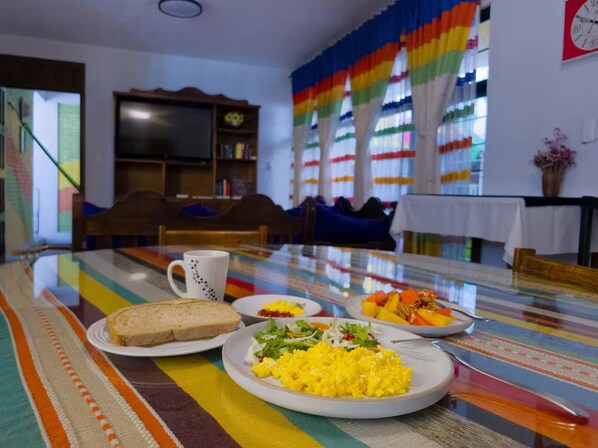 A dining area with a table set for breakfast, including toast, scrambled eggs, and a salad.