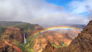 A canyon with a waterfall and a rainbow.