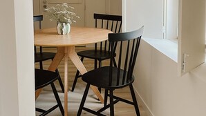 A dining area with a wooden table, black chairs, a vase with flowers, and a hanging light fixture.