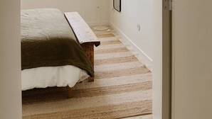 A bedroom with a bed, a window, a floor lamp, and a door.