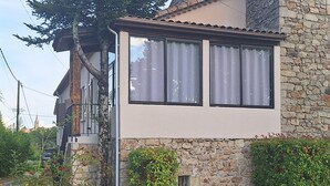 Una casa de dos pisos con fachada de piedra, un balcón y una ventana pequeña.