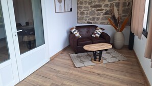 Una sala de estar acogedora con un sofá de cuero marrón, una mesa de centro de madera y una pared de piedra.