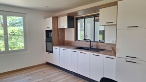Una cocina moderna con armarios blancos, encimera de madera y grifo negro.