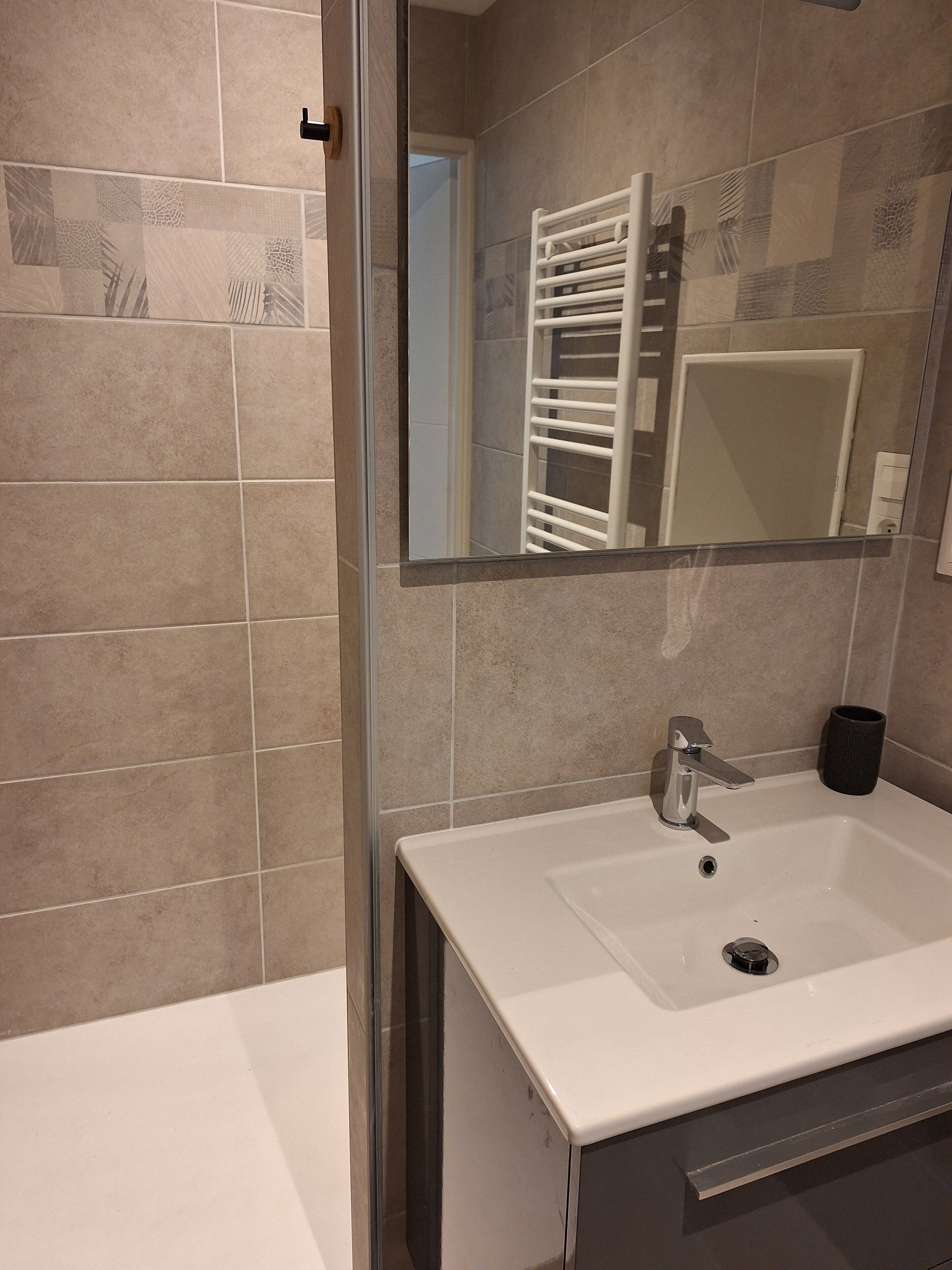 A bathroom with a white sink, a mirror, and a towel rack.