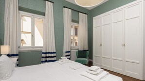 A hotel room with a bed, a chair, a radiator, and a wardrobe. - Fossi Street Central Apartment (Florence)