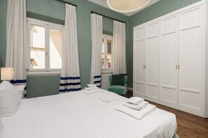 A hotel room with a bed, a chair, a radiator, and a wardrobe.