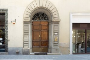 A large wooden double door with a metal arch above it, flanked by two columns. - Fossi Street Central Apartment (Florence)