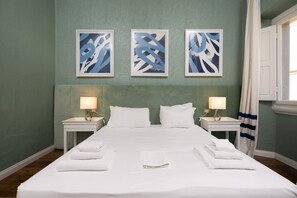A hotel room with a large bed, two bedside tables with lamps, and three abstract paintings on the wall. - Fossi Street Central Apartment (Florence)