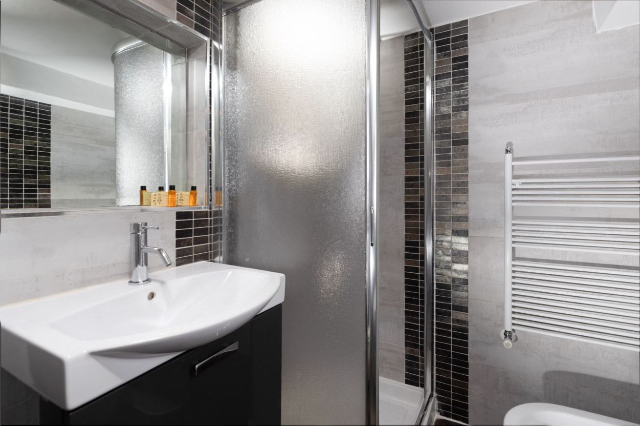 A modern bathroom with a white sink, a mirror, and a glass shower enclosure.