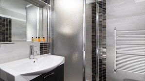 A modern bathroom with a white sink, a mirror, and a glass shower enclosure. - Fossi Street Central Apartment (Florence)