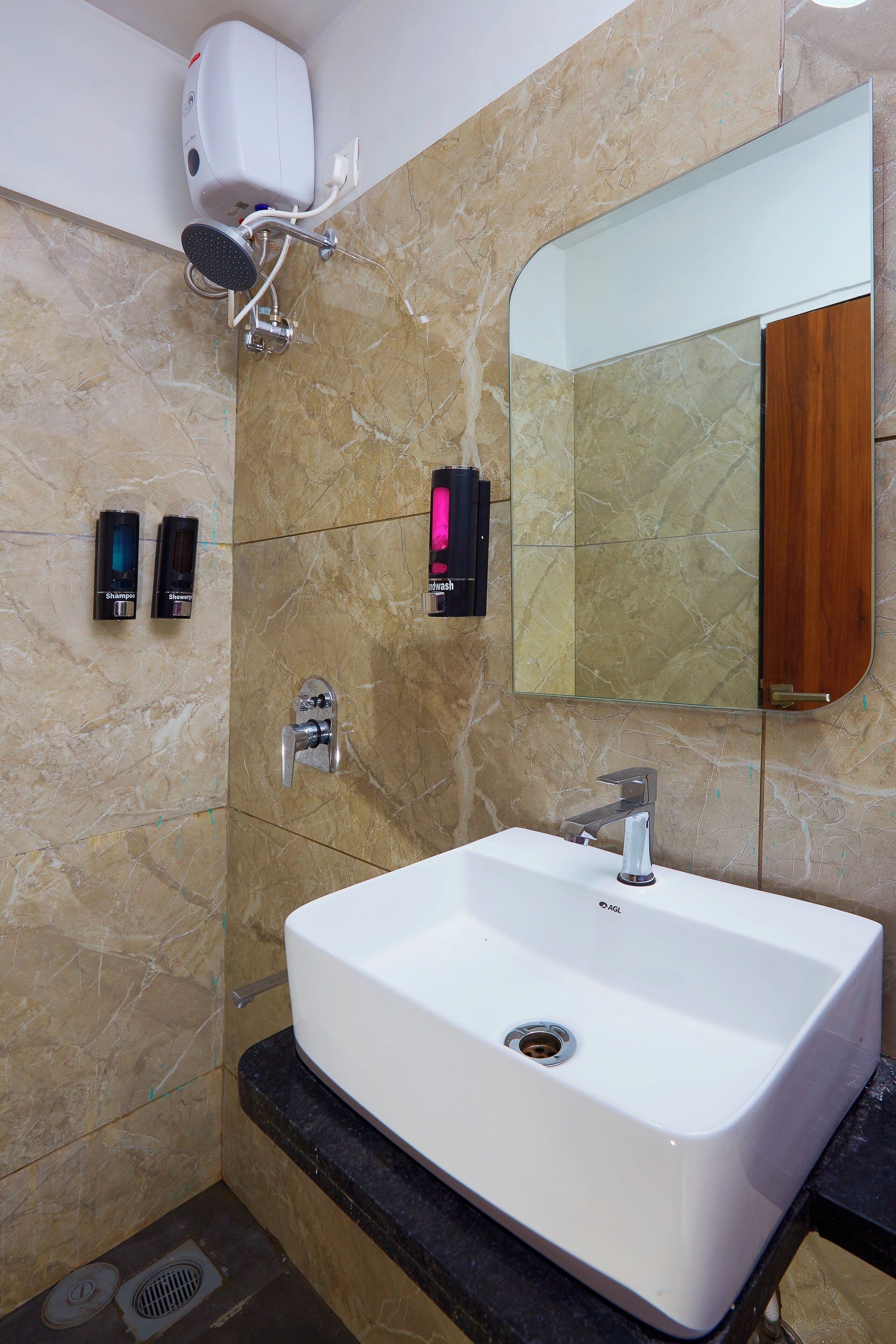 A modern bathroom with a white sink, a handheld showerhead, and two shampoo dispensers mounted on the wall.