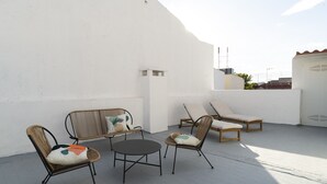A rooftop terrace with wicker chairs and a small round table, white walls, and a clear sky. - Waou Terrace House I (Madrid)