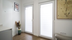 A room with a white door, a framed picture on the wall, a vase with dried plants, and a painting. - Waou Terrace House I (Madrid)